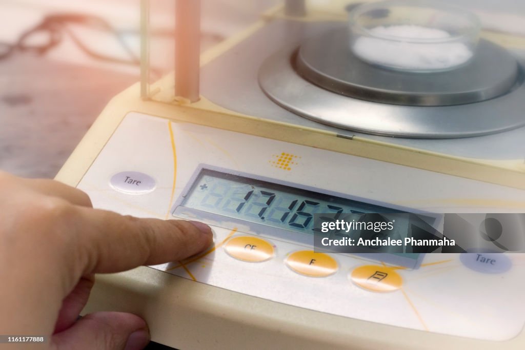 Scientist is weighing the sample with electronic weighing scales (Laboratory balance Weighing) in chemical laboratory.