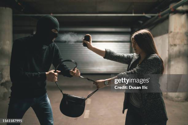 vrouw met behulp van pepper spray voor zelfverdediging tegen dief - pepper spray stockfoto's en -beelden