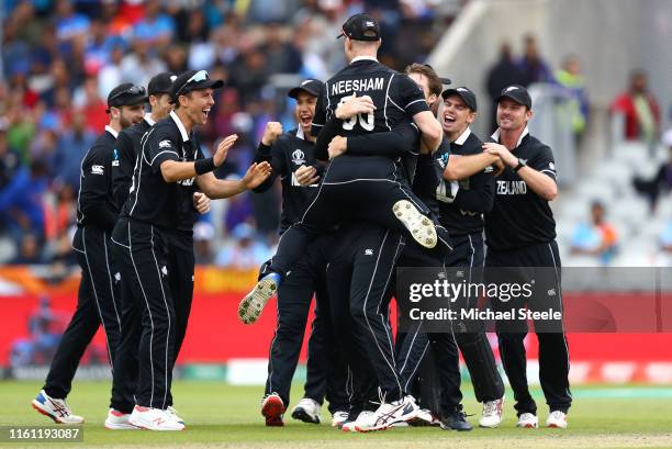 Jimmy Neesham of New Zealand celebrates with Martin Guptill after running out MS Dhoni of India during resumption of the Semi-Final match of the ICC...