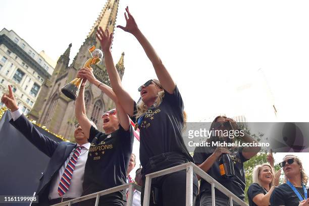 United States Soccer Federation president Carlos Cordeiro, Megan Rapinoe, Allie Long and Alex Morgan celebrate and hold up the trophy while riding on...