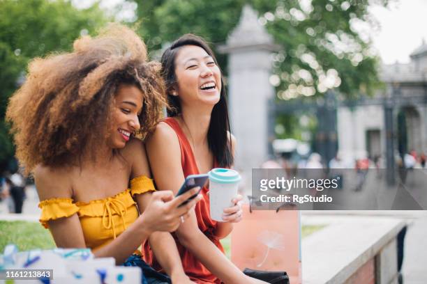 glückliche mädchen mit telefon im freien - asian friends coffee stock-fotos und bilder