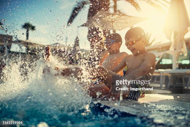 スイミングプールで水しぶきを楽しむ子供たち - リゾート　家族 ストックフォトと画像