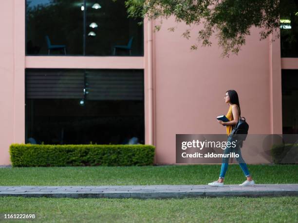 college meisje lopen door de campus - college student holding books stockfoto's en -beelden