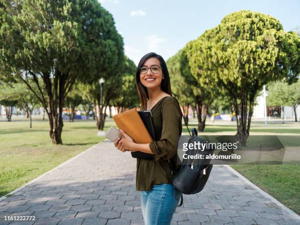 latina college meisje te kijken naar de camera met een glimlach - universiteit stockfoto's en -beelden