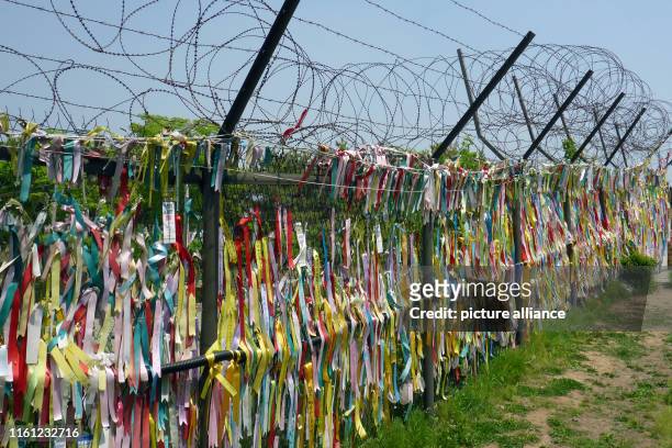 May 2019, South Korea, Paju: Colourful ribbons with wishes written on them hang from a barbed wire fence on the South Korean side of the "Common...
