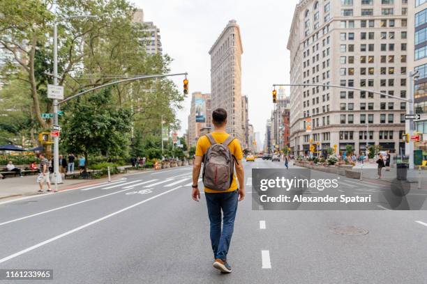 young man walking on fifth avenue towards flatiron building, rear view - rear stockfoto's en -beelden