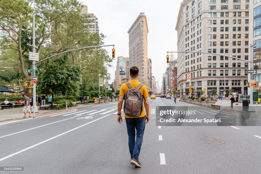 Young man walking on Fifth Avenue towards Flatiron Building, rear view