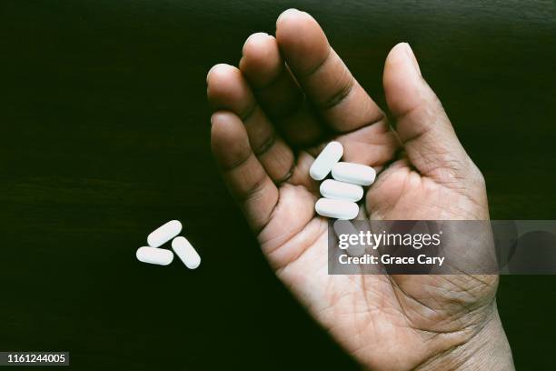 woman's cupped hand holds white pills - acetaminophen stock-fotos und bilder