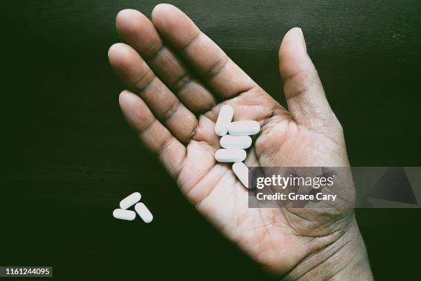 woman's outstretched hand holds white pills - african american woman with tablet stockfoto's en -beelden