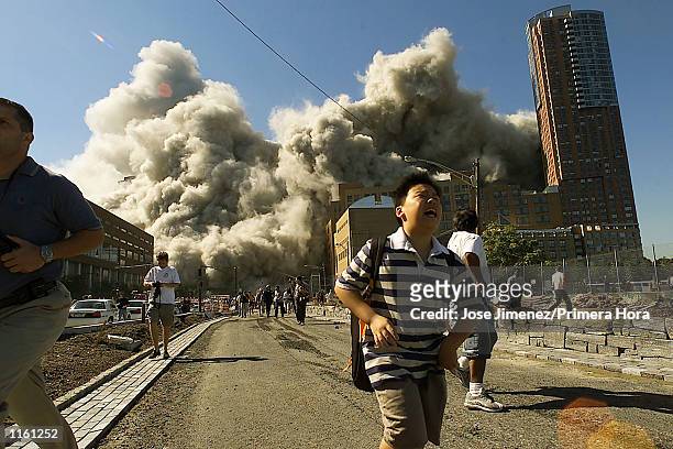 People run away as the second tower of World Trade Center crumbles down after a plane hit the building September 11, 2001 in New York City.
