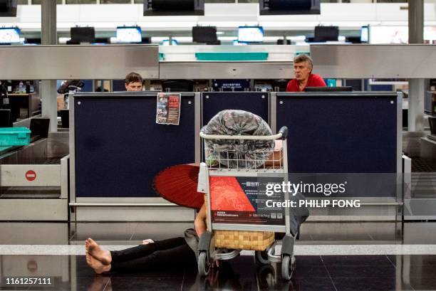 Traveler rests at a check-in booth at Hong Kong's international airport following a protest against the police brutality and the controversial...