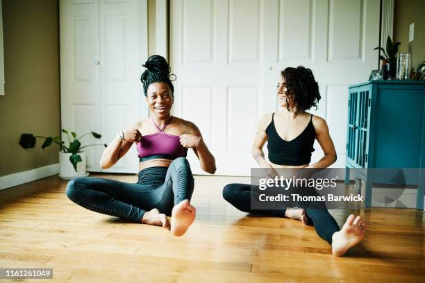 female friends laughing together during yoga workout in home - home workout stockfoto's en -beelden