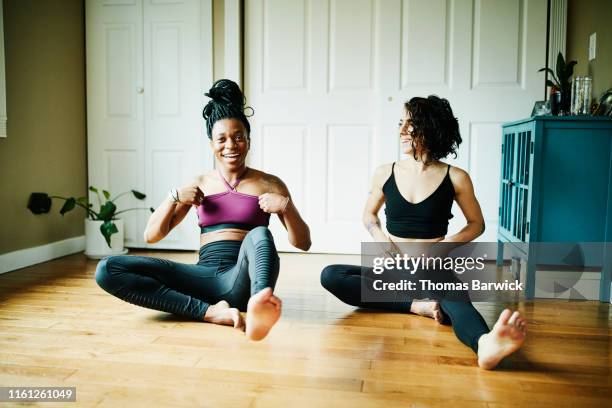 female friends laughing together during yoga workout in home - at home workout stock pictures, royalty-free photos & images