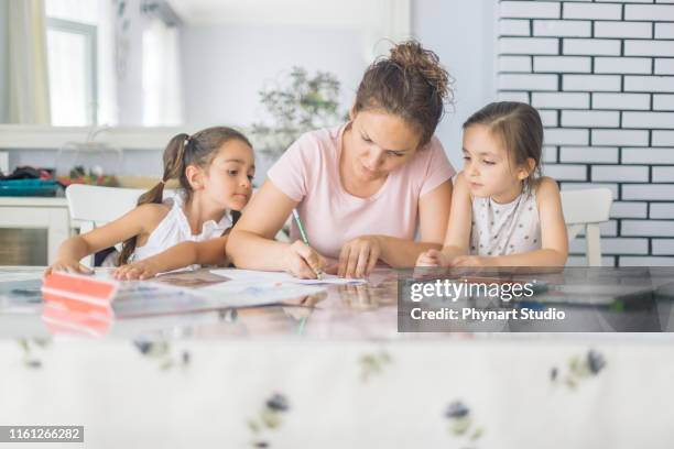 mother helping daughters with homework - family homework stock pictures, royalty-free photos & images
