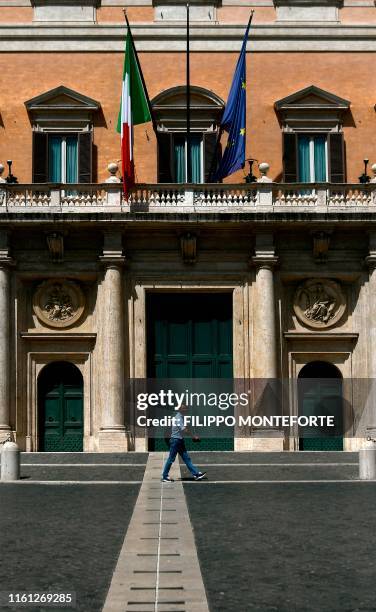 Man walks in front of the main entrance of Montecitorio, the Italian Parliament, on August 12, 2019 in Rome. - The Upper House could be recalled to...