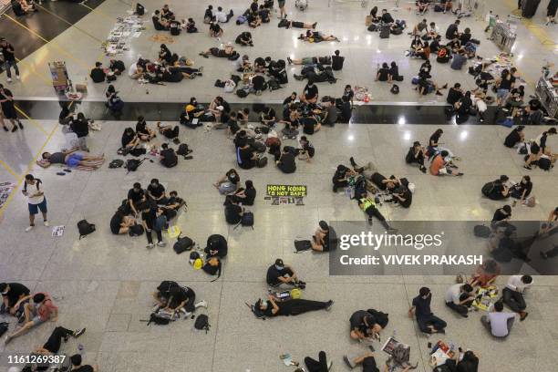 Protesters sit on the floor of the arrivals hall of Hong Kong's international airport following a protest against police brutality and the...