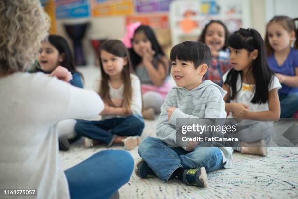 multi-ethnic group of preschool children are dancing to music with their caucasian teacher - rhythm stock pictures, royalty-free photos & images