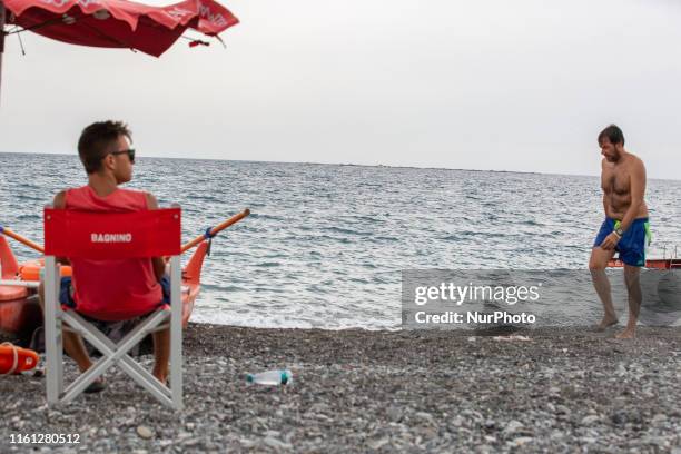 Man walking and a lifeguard looks at the right, in Lavagna, Italy, on August 12, 2019. As the weather was cloudy and rainy in Northern Italian region...