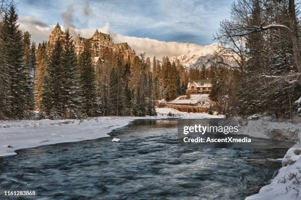 uitzicht over de rivier naar het hotel in het bos in de winter - banff springs hotel stockfoto's en -beelden