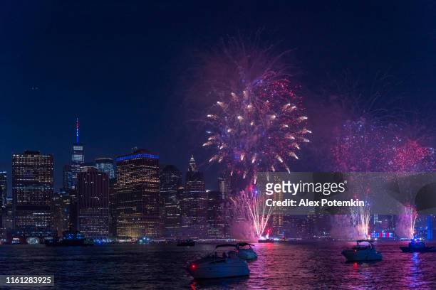 menigte kijken naar de kleurrijke vakantie vuurwerk op east river, in de voorkant van manhattan downtown, van vele jachten en boten. - new york spring spectacular stockfoto's en -beelden