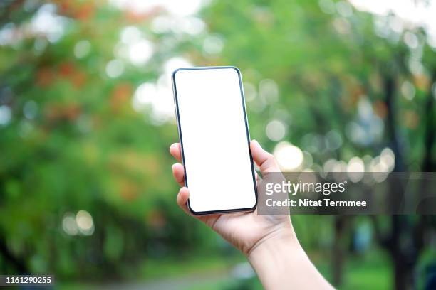 hand hold smartphone on green blurred background. blank screen mobile phone for graphic display montage. - people montage stock pictures, royalty-free photos & images