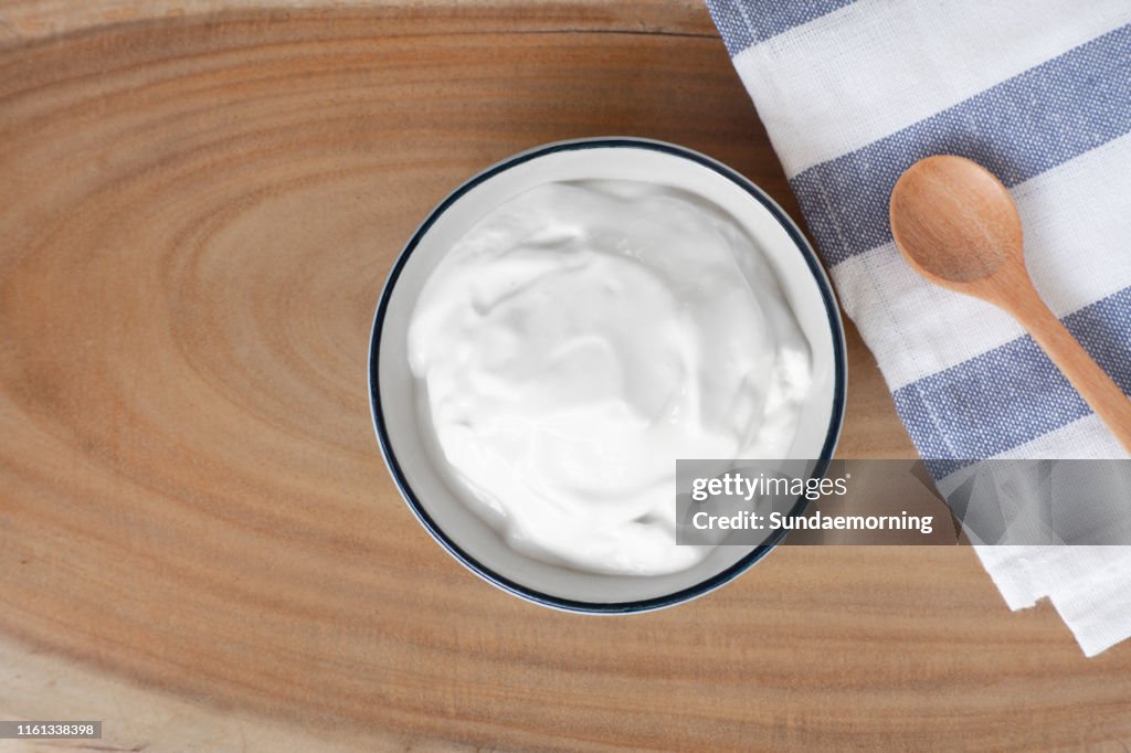 Naturlig hemlagad vanlig ekologisk yoghurt i kopp på trä textur bakgrund, kopiera utrymme