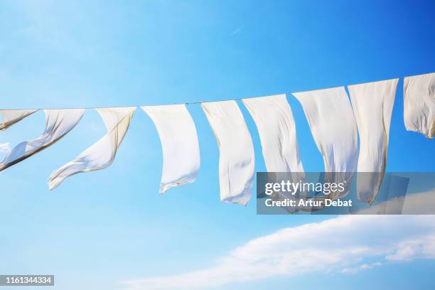 white sheets flying with the wind and blue sky in greece. - white laundry foto e immagini stock