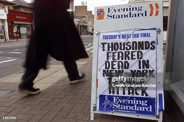 Pedestrian walks past an evening newspaper billboard whose headline reports the terrorist attacks on the United States September 11, 2001 in London.