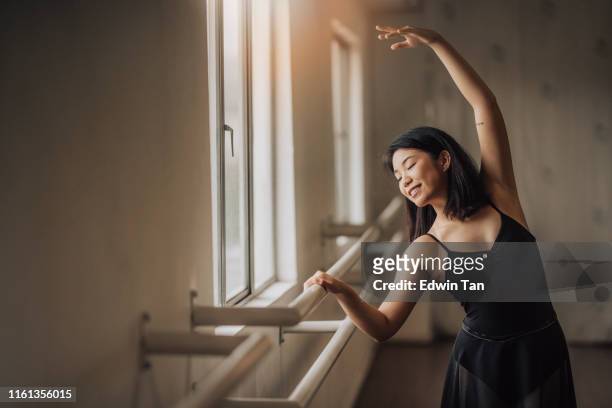 an asian chinese female ballet dancer practising in ballet studio near window waist up