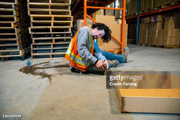 an industrial, warehouse, workplace safety topic.  an employee falls injuring himself by slipping on a plastic water bottle. - stumble stock pictures, royalty-free photos & images