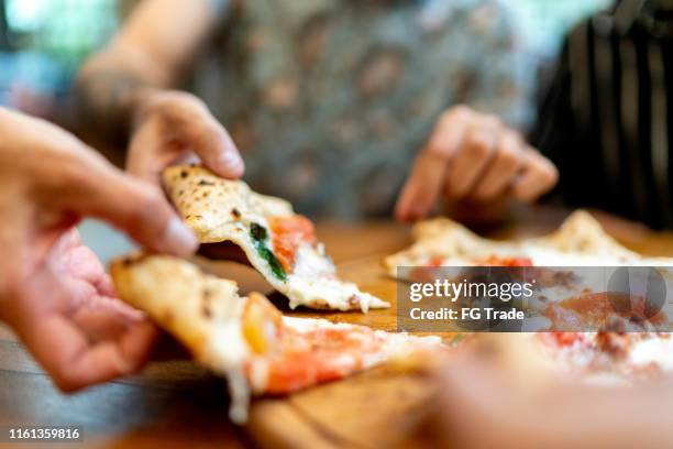 friends getting slices of pizza, using hands - pizza restaurant stock pictures, royalty-free photos & images