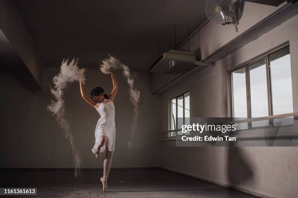 an asian chinese female teenager ballet dancer practising in ballet studio during day time dancing with powder
