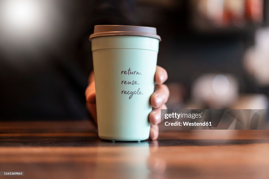 Hand holding deposit cup for Coffee to go, close-up