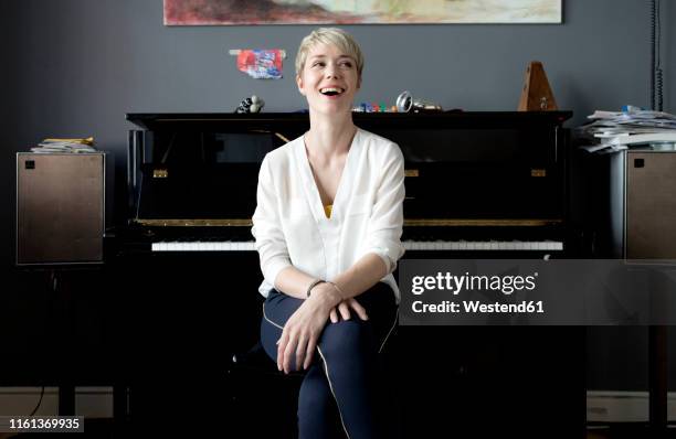 portrait of laughing woman sitting in her music room in front of piano - pianist front fotografías e imágenes de stock