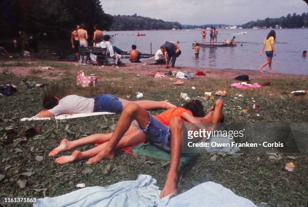Young people relaxing by a lake during the the Woodstock music festival, New York, US, August 1969. )