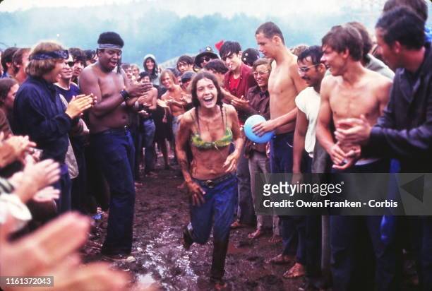 Woman running through the mud at the Woodstock Music Festival, New York, US, 17th August 1969. )