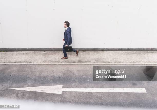 businessman walking at road with arrow sign - single lane road - fotografias e filmes do acervo