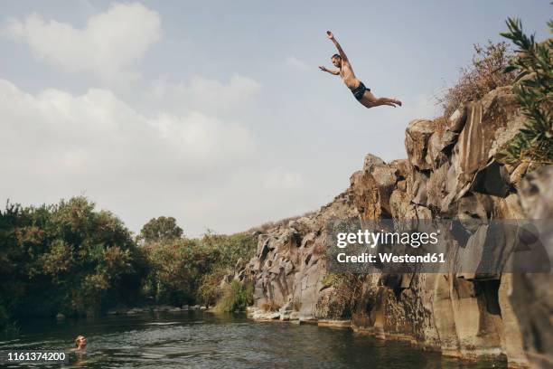 young man jumping from a cliff, yehudiya reserve, golan, israel - jumping into lake stock pictures, royalty-free photos & images