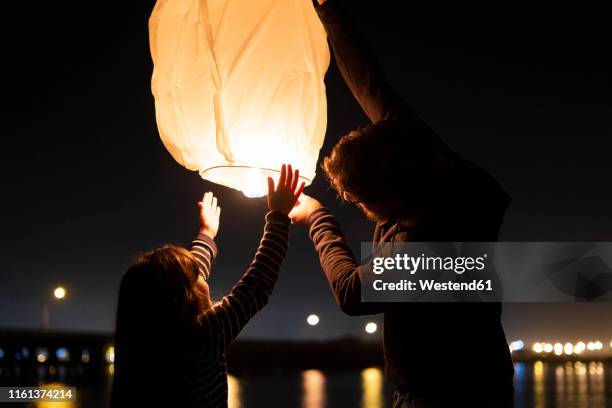 father and daughter preparing a sky lantern on the beach at night - wish fotografías e imágenes de stock