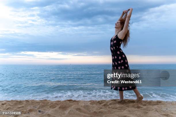 happy young woman dancing on the beach in the evening - barefoot redhead ストックフォトと画像