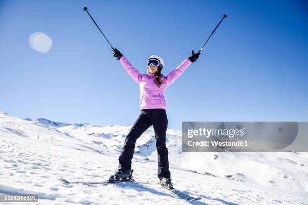 happy woman raising her ski poles in snow-covered landscape in sierra nevada, andalusia, spain - roze handschoen stockfoto's en -beelden