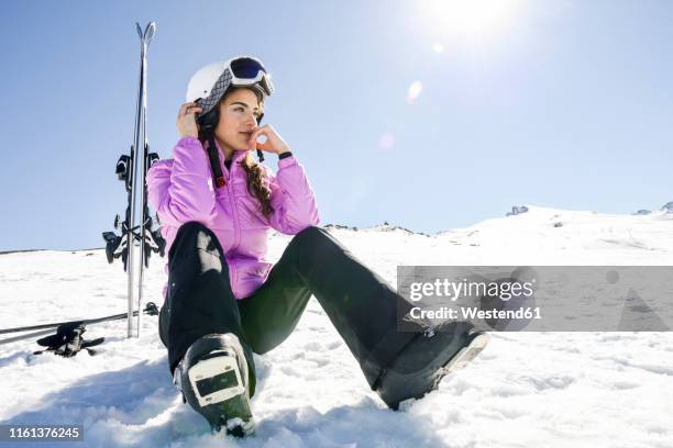 woman taking a break after skiing sitting on the snowy ground in sierra nevada, andalusia, spain - mountain snow skiing foto e immagini stock