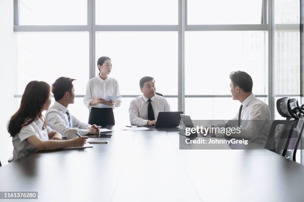 mature chinese ceo speaking with associates in boardroom meeting - round table imagens e fotografias de stock