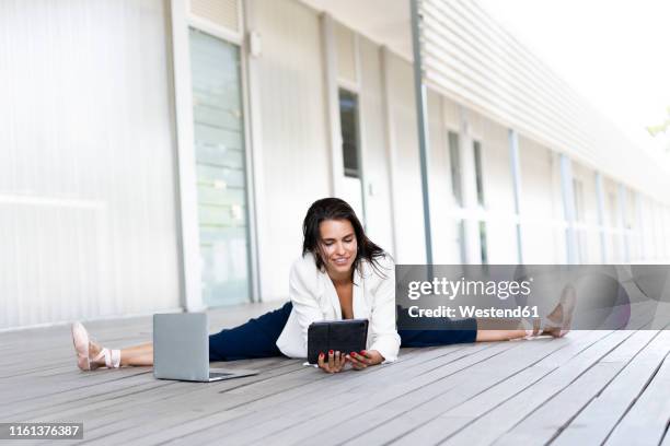 female balett dancer sitting on the ground, using tablet and laptop - balett stock-fotos und bilder
