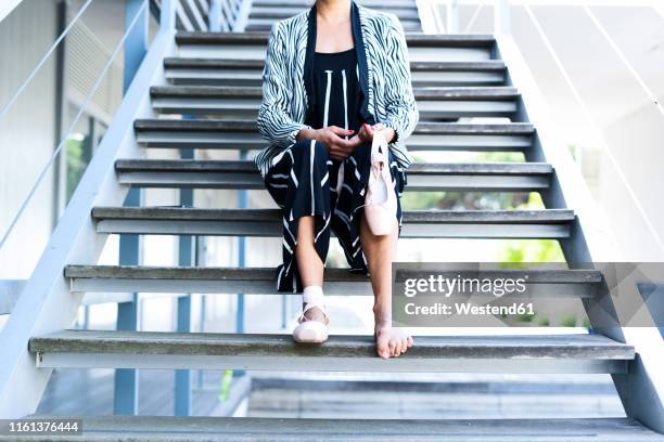 female dancer with ballet shoes sitting on steps, neck down - ballet feet hurt stock pictures, royalty-free photos & images