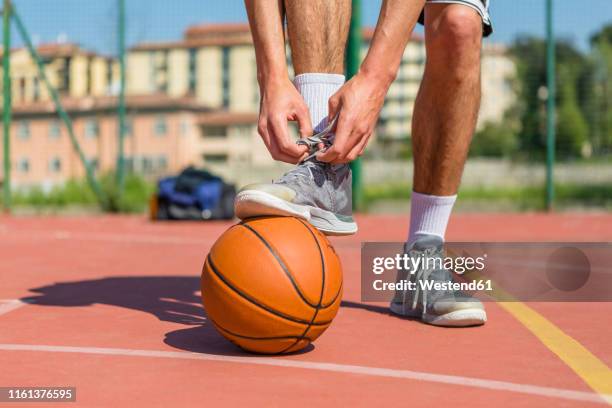 young basketball player tying shoes - basketball shoe stock pictures, royalty-free photos & images