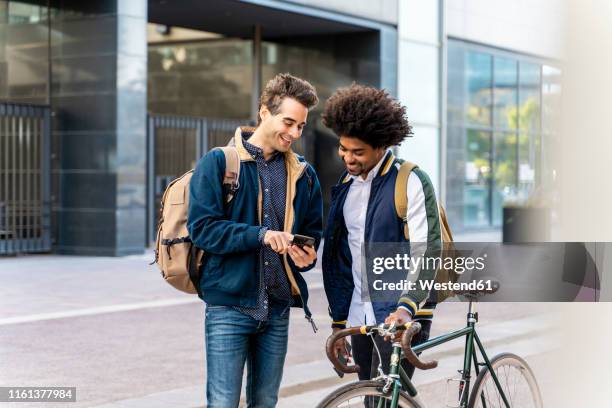 two happy casual businessmen with cell phone meeting in the city, barcelona, spain - man showing phone photos et images de collection