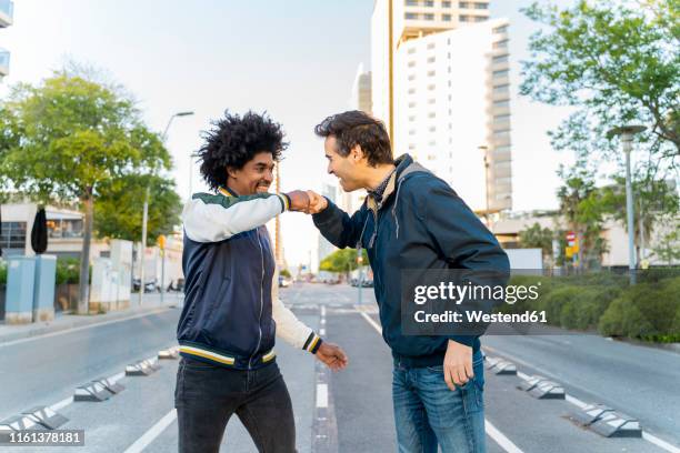 two happy friends fist bumping in the city, barcelona, spain - fist bump photos et images de collection