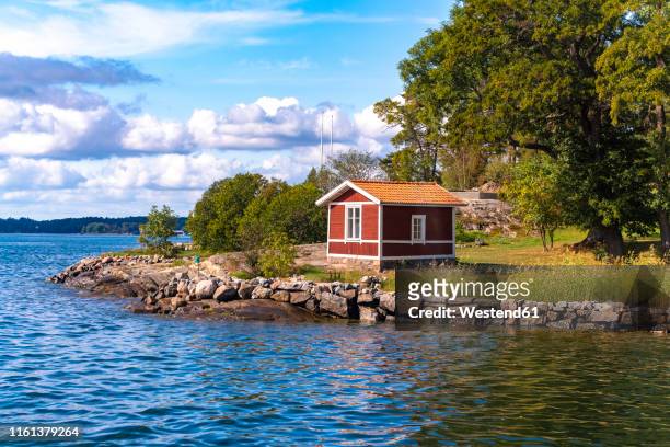 wooden hut in traditional red at the archipelago near stockholm, sweden - stockholm beach stock pictures, royalty-free photos & images
