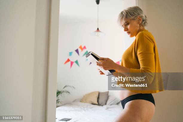 woman standing in bedroom at home holding notepad - frau in slip stock-fotos und bilder